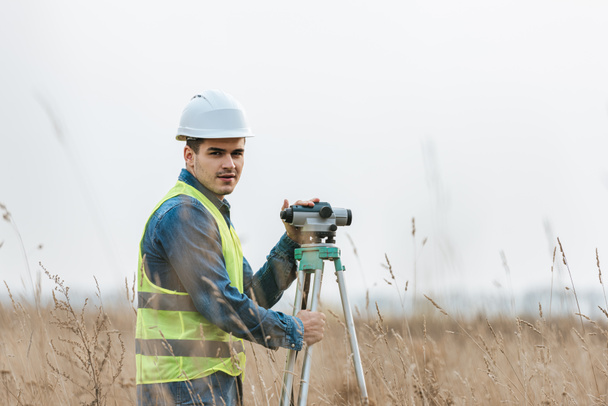 Surveyor avec niveau numérique regardant la caméra sur le terrain
  - Photo, image