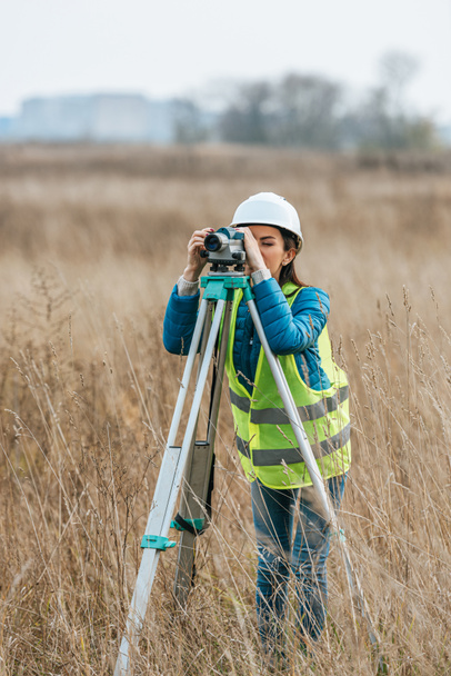 Female surveyor working with digital level in field - Foto, afbeelding