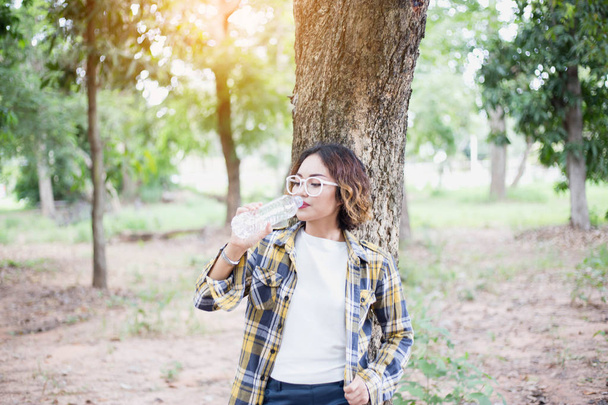 Девушка пьет воду из бутылки в лесу
 - Фото, изображение