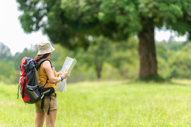 Student asian women and traveler with backpack adventure holding map to find directions location and leisure destination place in the jungle forest outdoor for study and education nature. Travel and Lifestyle Concept - Foto, Imagen