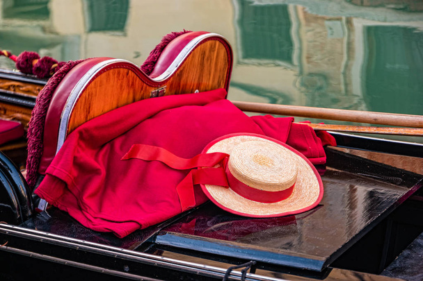 A close up of a gondola with oars, gondolier hat and red blanket in Venice, Italy - Photo, Image