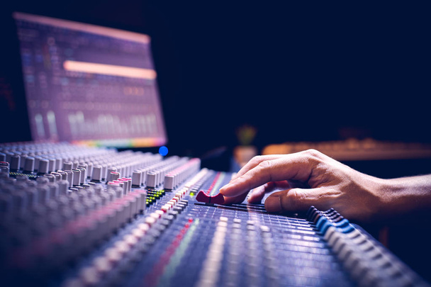 male producer, sound engineer hands working on audio mixing console in broadcasting, recording studio - Photo, image