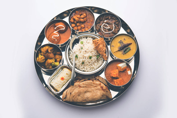 Alimento vegetariano indio Thali o plato incluye paneer butter masala, dal makhani / tarka, chole papad, kofta curry, gulab jamun, aloo-gobi sabji, chapati y arroz con dulce bengalí servido
 - Foto, imagen