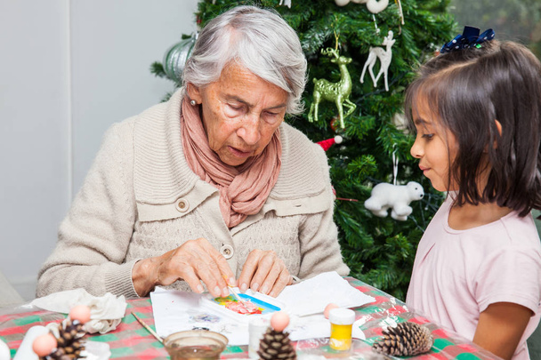 Little girl having fun while making christmas Nativity crafts with her grandmother - Real family - Foto, afbeelding