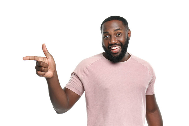 Όμορφος Αφρο-Αμερικανός άνθρωπος που δείχνει κάτι σε λευκό φόντο - Φωτογραφία, εικόνα