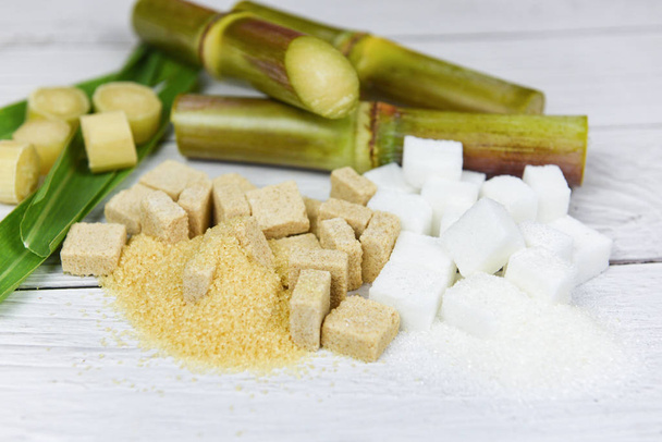Zuccheri a cubetti bianchi e marroni e canna da zucchero sul tavolo di legno
  - Foto, immagini