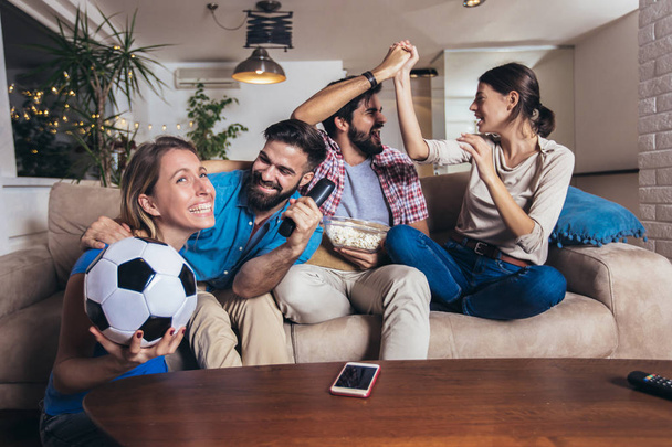 Friends having fun by watching football match at home, indoors. - Photo, image