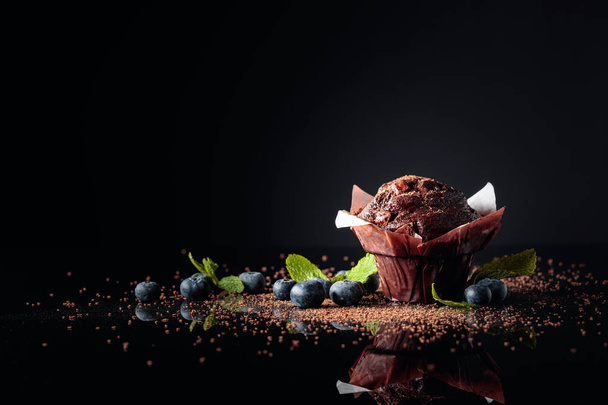 Muffin de chocolate espolvoreado con migas de chocolate en un refl negro
 - Foto, Imagen