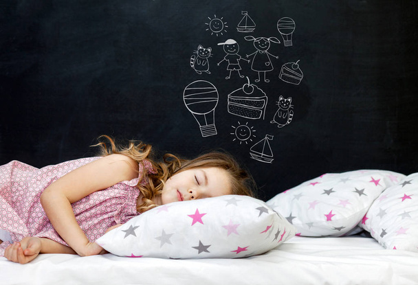 Okouzlující holčička předškolního věku spí v posteli na polštáři s hvězdami. Čas jít spát. Kreslení o snech dítěte: koťátko, dezert, dobrodružství a přátelství. Kopírovat prostor - Fotografie, Obrázek