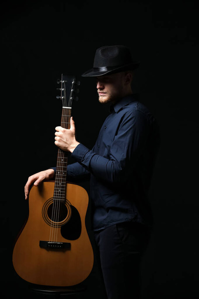 Handsome man with guitar on dark background - Foto, Bild