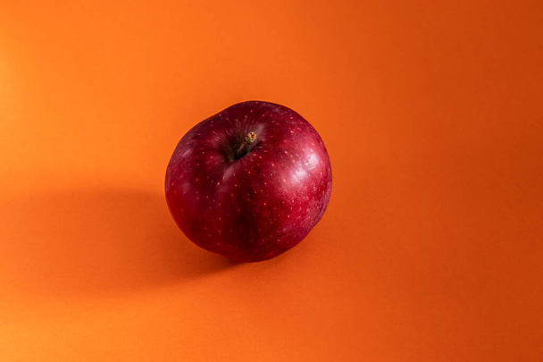 ripe red apple lies on an orange background - 写真・画像