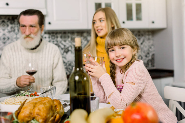 familia, vacaciones, generación y concepto de personas - familia sonriente cenando en casa, se centran en la niña sonriente sosteniendo el vaso con jugo
 - Foto, imagen