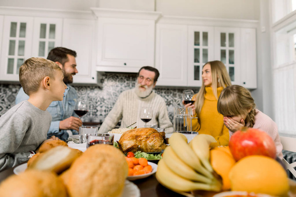 Fijne Thanksgiving dag. Familie zit aan tafel en viert vakantie. Grootvader, ouders en kinderen. Traditioneel diner. Focus op de kalkoen - Foto, afbeelding