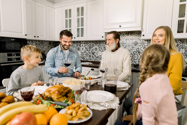 Retrato de una gran familia sentada en la mesa festiva y mirándose, hablando y sonriendo. Concepto de cena de Acción de Gracias
 - Foto, Imagen