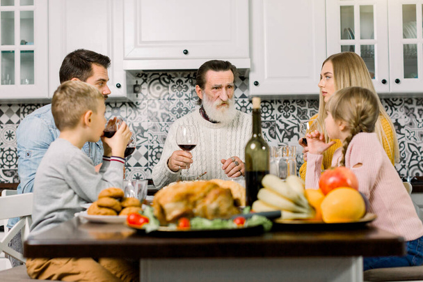 Famiglia felice multi generazione alzare i calici per fare un brindisi al loro tavolo del Ringraziamento. Nonno, genitori e figli che cenano insieme
 - Foto, immagini