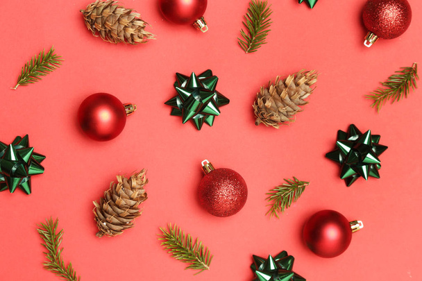 Karácsonyi dekoráció. Piros karácsonyi fényes golyók és fenyőágak ünnepi vörös háttérrel. Karácsonyi díszek elrendezése. - Fotó, kép