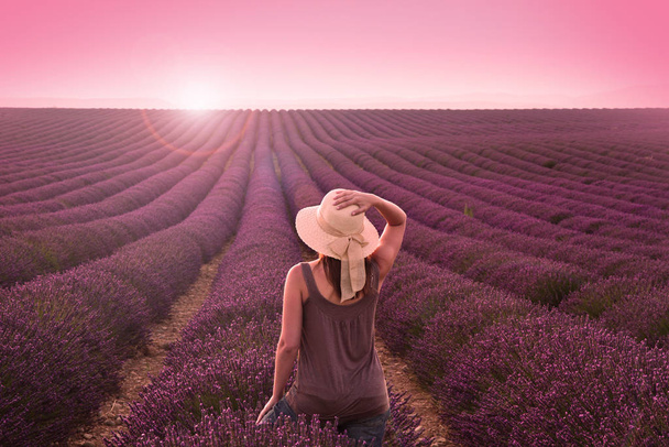 A girl walks in the lavender fields and shows the sun at sunset - Fotó, kép