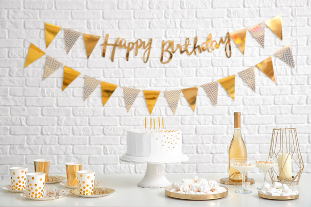 Barra de doces saborosa para festa de aniversário na mesa perto da parede de tijolo branco
 - Foto, Imagem