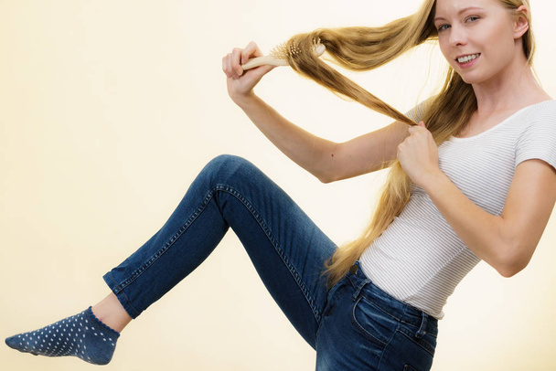 Blonde girl brushing her long hair - Фото, зображення