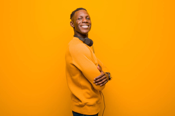 young african american black man against orange wall with headphones - Zdjęcie, obraz