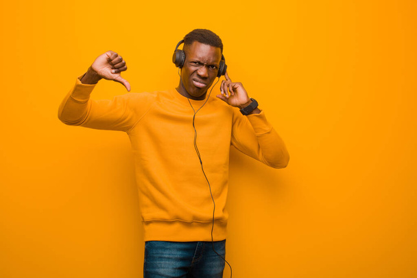 young african american black man against orange wall with headphones - Fotoğraf, Görsel