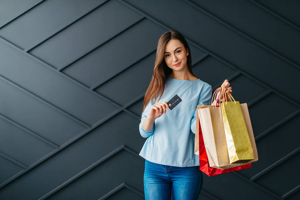 Happy woman holding credit card and bags with purchases, black friday concept - Foto, imagen