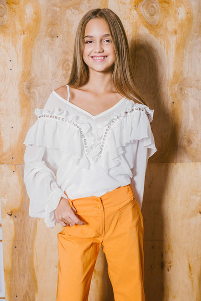 Attractive young girl with blond hair and evening make-up in retro flared pants and a chiffon boho blouse  - Foto, Imagen