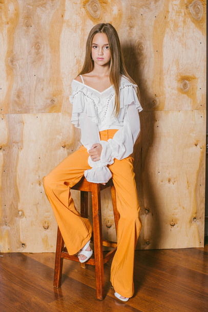 Attractive young girl with blond hair and evening make-up in retro flared pants and a chiffon boho blouse  - Foto, Imagem