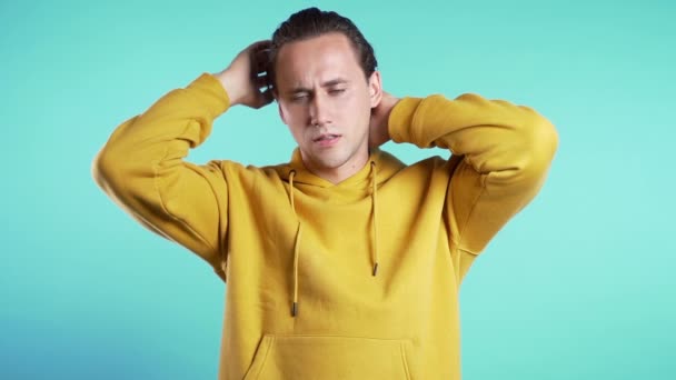 Frustrated european man in yellow wear over blue wall background. Guy is tired of work or studying, he disappointed, helpless - Filmati, video