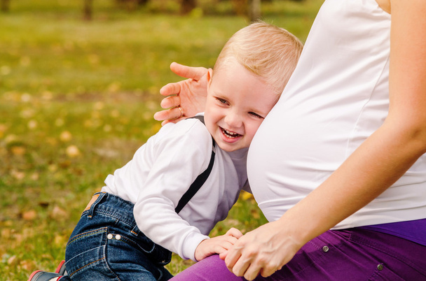 Happy smiling child near pregnant mom tummy - Foto, immagini