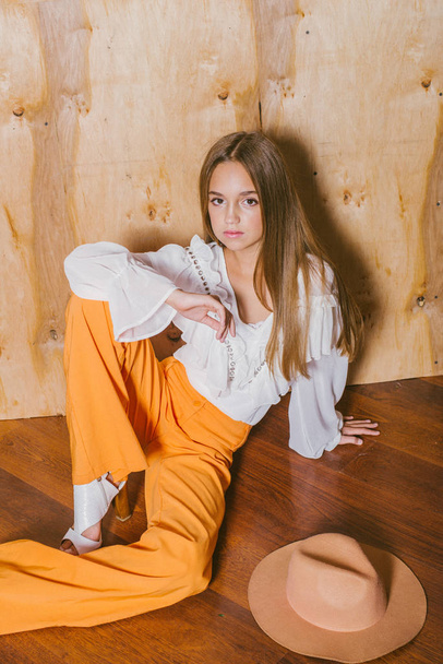 Attractive young girl with blond hair and evening make-up in retro flared pants and a chiffon boho blouse  - Foto, afbeelding