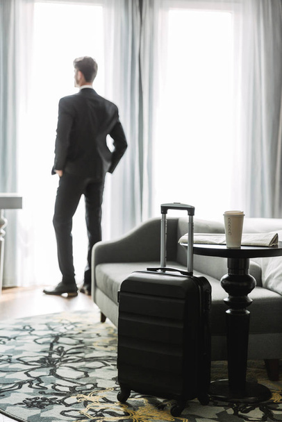Image of successful young man standing by window in hotel apartm - Foto, immagini