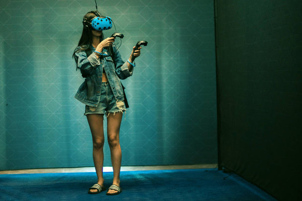 A girl with a virtual reality headset and joystick playing video - Foto, Bild