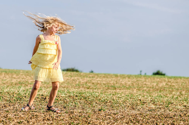 spontaneous child in yellow dress dancing wildly in rural path  - Fotó, kép