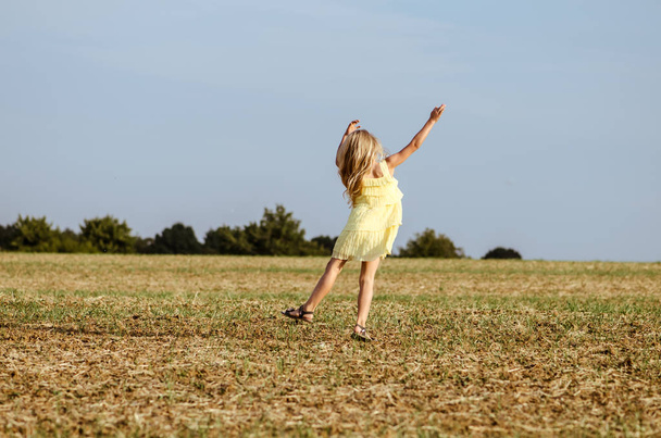 niño espontáneo en vestido amarillo bailando salvajemente en el camino rural
  - Foto, imagen