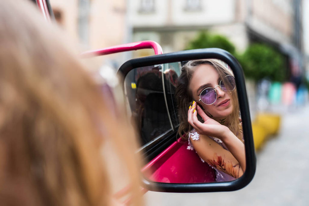 Portrait of young gil wearing dress and violet sunglasses. tattoes over her arms and face watching in car mirror. Close up. City walk. Subculture attributes. - Fotoğraf, Görsel