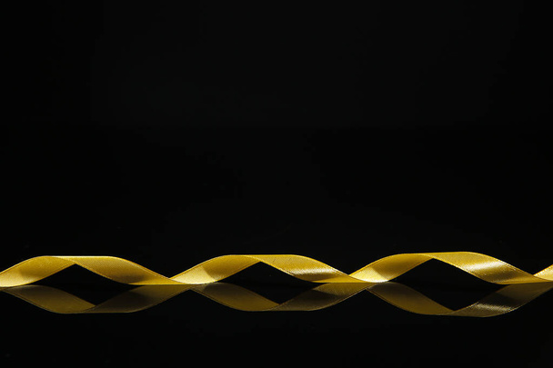 Beautiful golden ribbon on dark background - Фото, зображення