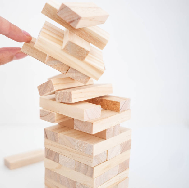 Close up of falling wooden bricks tower and a hand. finance fall concept. Planning, risk and strategy in business, businessman and engineer gambling placing wooden block on a tower. - Foto, afbeelding