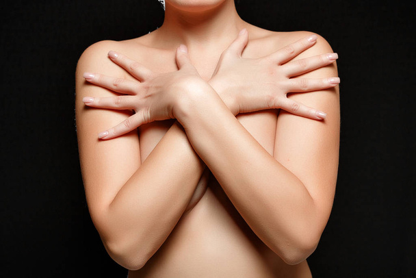 mujer morena joven desnuda cubre sus pechos. sobre negro aislado
 - Foto, Imagen