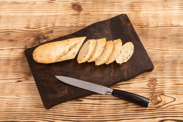 Sliced rye bread and knife on a cutting board - Фото, зображення