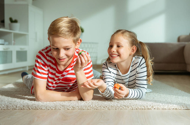 Portrait of two cheerful children laying on the floor and playin - Foto, Bild