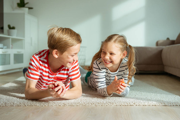 Portrait of two cheerful children laying on the floor and playin - Fotó, kép