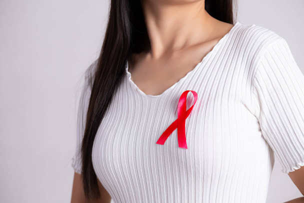 Primo piano del nastro rosso sul petto della donna per sostenere la Giornata dell'AIDS. Concetto di sanità, medicina e sensibilizzazione all'AIDS. - Foto, immagini