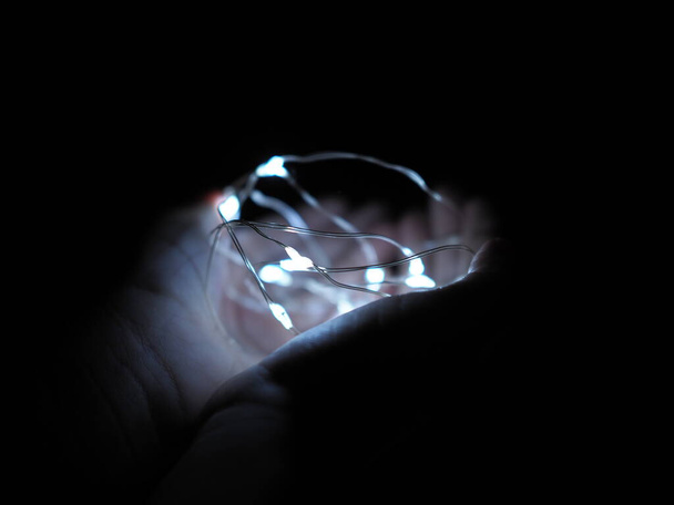 Çocuğun elleri Bokeh ışıklarıyla Noel çelengini tutuyor - Fotoğraf, Görsel