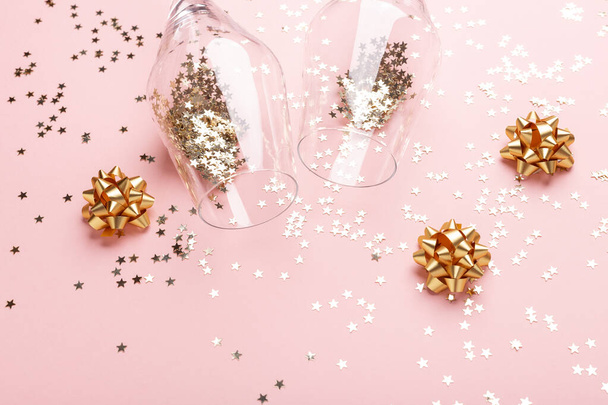 Christmas flat lay. Champagne glasses and gold decoration on pink background - Photo, image
