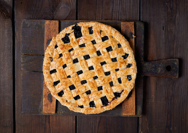 pastel de grosella negra redonda al horno sobre fondo de madera
 - Foto, Imagen