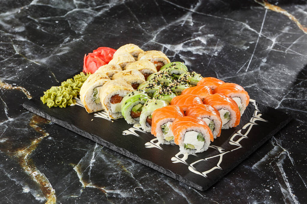 Various kinds of sushi served on black marble background. Sushi menu for Japanese food. Japanese sushi set. Rolls with tuna, salmon, shrimp, crab, caviar and avocado. Horizontal photo. - Фото, зображення