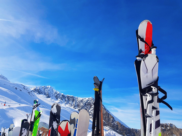 Imagem de esquis multicoloridos e snowboards na neve no resort de inverno à tarde
. - Foto, Imagem