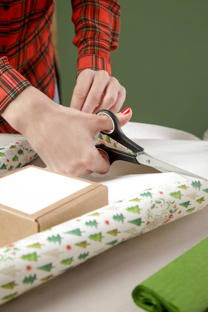Frau schneidet Geschenkpapier auf dem Schreibtisch, Weihnachtsgeschenkkonzept - Foto, Bild