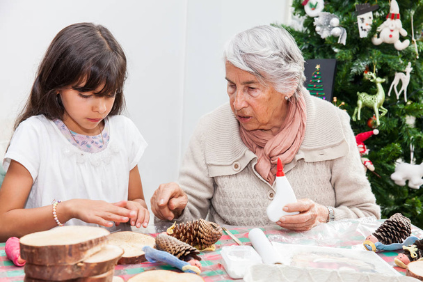 Grandmother teaching her granddaughter how to make christmas Nativity crafts - Real family - 写真・画像